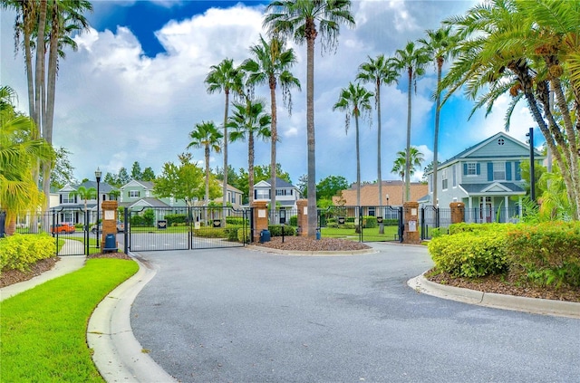 view of street with street lights, a gated entry, curbs, a gate, and a residential view