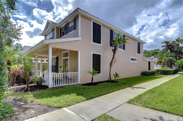 view of property exterior with a porch, a lawn, and stucco siding