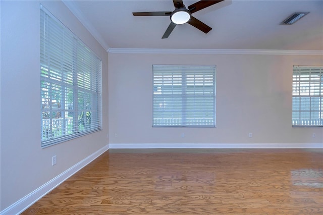 empty room with ceiling fan, wood finished floors, visible vents, baseboards, and ornamental molding