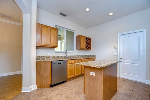 kitchen featuring a center island, arched walkways, visible vents, dishwasher, and baseboards