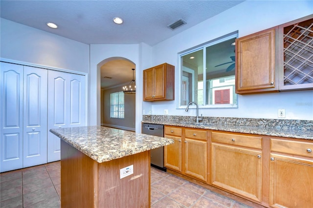 kitchen featuring visible vents, arched walkways, a kitchen island, stainless steel dishwasher, and a sink