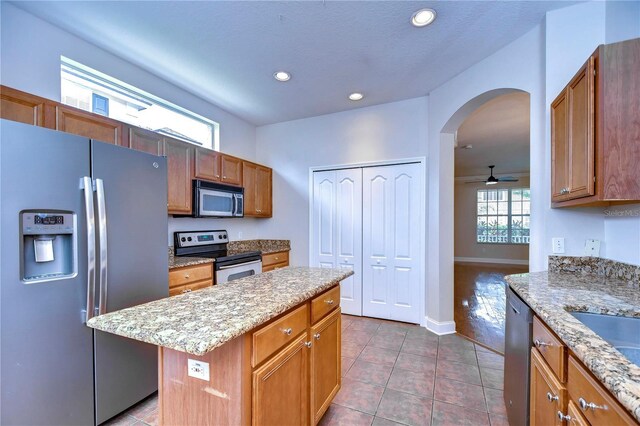 kitchen featuring arched walkways, a kitchen island, tile patterned flooring, stainless steel appliances, and recessed lighting