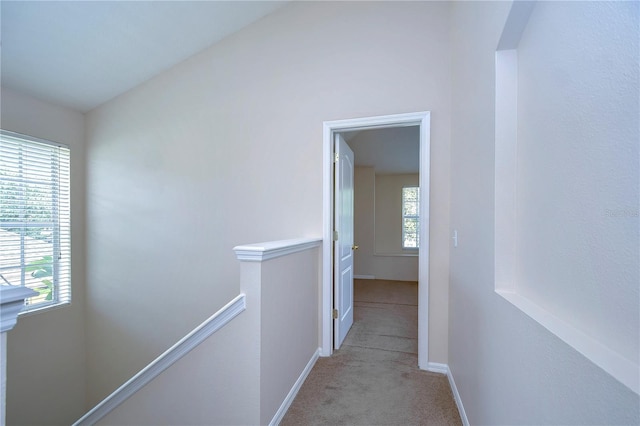 hall featuring lofted ceiling, carpet, an upstairs landing, and baseboards