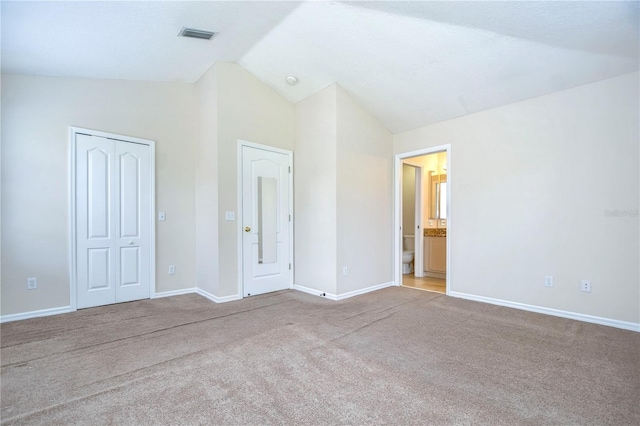 unfurnished bedroom featuring carpet floors, a closet, visible vents, vaulted ceiling, and baseboards