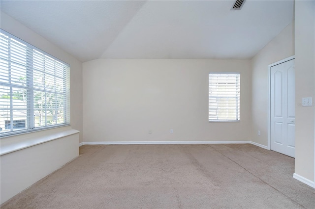 carpeted spare room with a healthy amount of sunlight, baseboards, visible vents, and vaulted ceiling