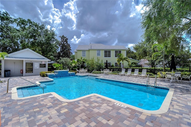 pool with a patio area, fence, and an outbuilding