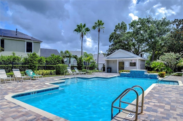 pool featuring a patio area, fence, and an outbuilding