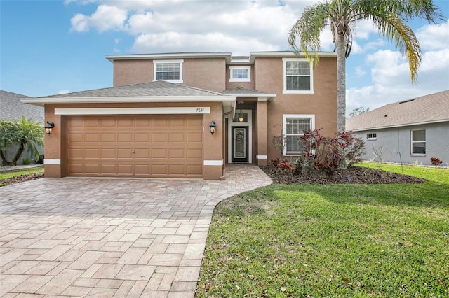 view of front of house featuring a garage, a front lawn, decorative driveway, and stucco siding