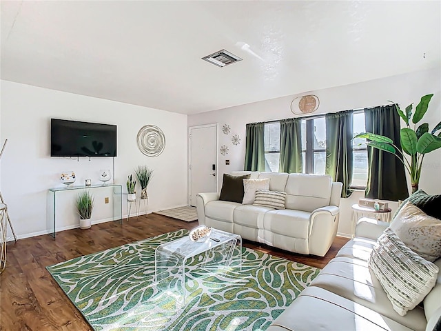 living area with wood finished floors, visible vents, and baseboards