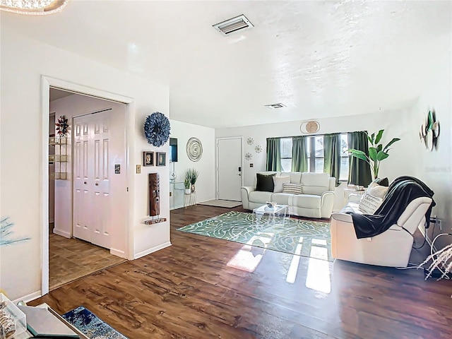 living area featuring visible vents, baseboards, and wood finished floors