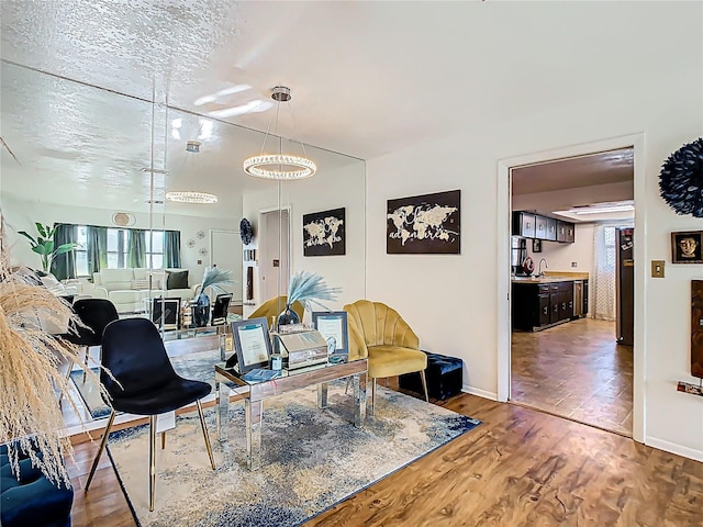 living area featuring plenty of natural light, a textured ceiling, baseboards, and wood finished floors