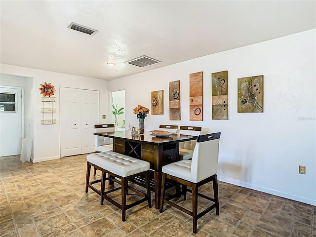 dining space with visible vents, baseboards, and stone finish flooring