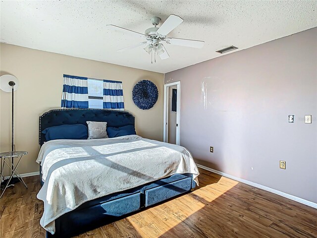 bedroom with visible vents, a textured ceiling, a ceiling fan, and wood finished floors