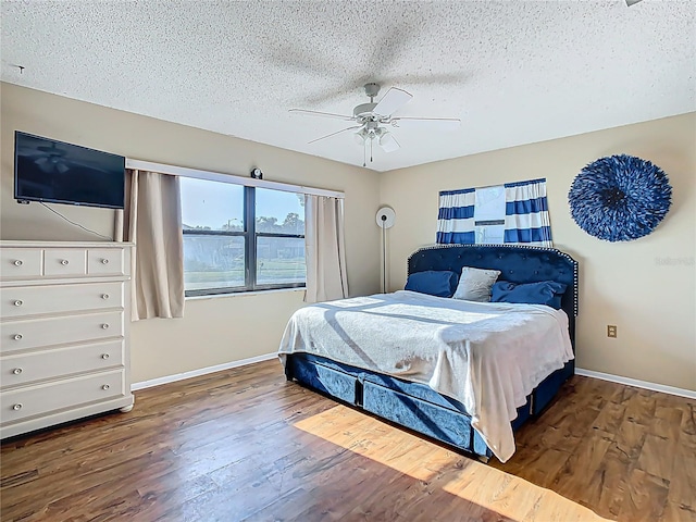 bedroom with ceiling fan, a textured ceiling, baseboards, and wood finished floors