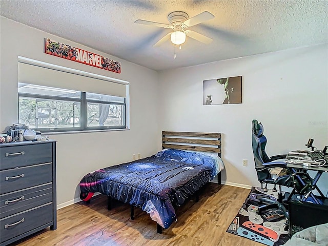 bedroom with ceiling fan, baseboards, a textured ceiling, and wood finished floors