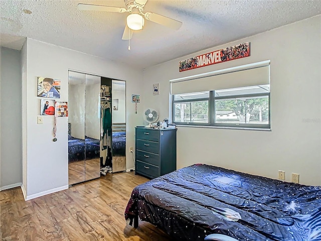 bedroom with a closet, baseboards, a textured ceiling, and wood finished floors