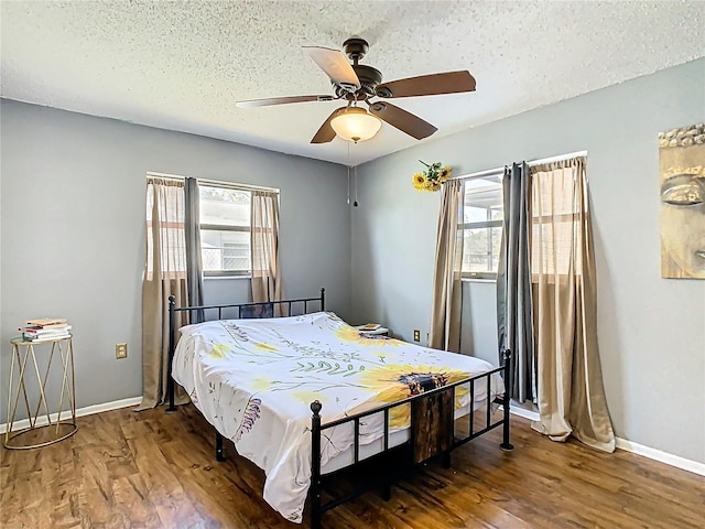 bedroom with baseboards, a textured ceiling, wood finished floors, and a ceiling fan