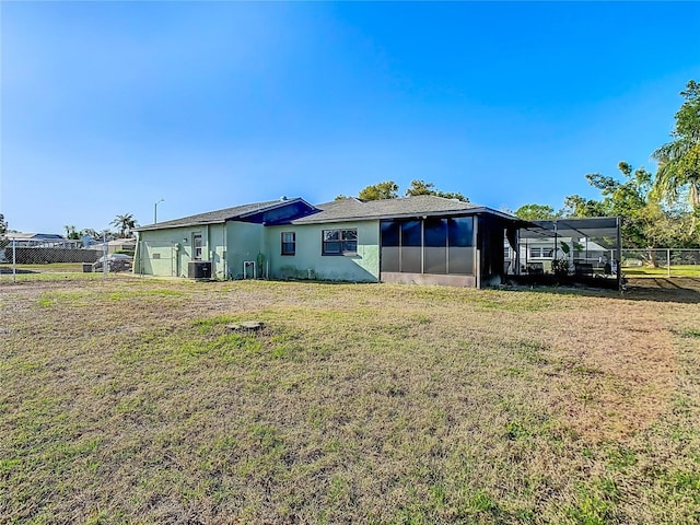 back of property with stucco siding, fence, a yard, cooling unit, and a sunroom