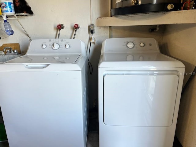 clothes washing area featuring laundry area, separate washer and dryer, and a textured wall