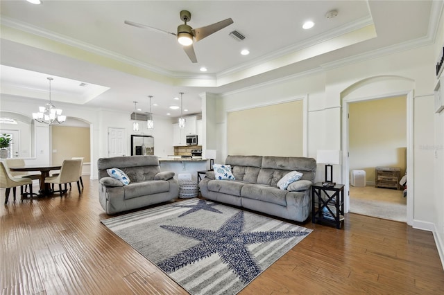 living room featuring visible vents, a raised ceiling, wood-type flooring, and crown molding