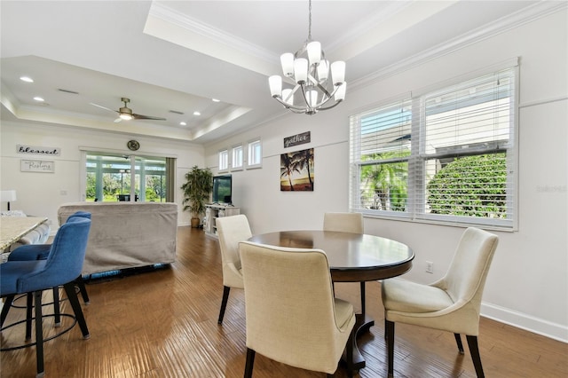 dining room featuring ornamental molding, baseboards, a tray ceiling, and wood finished floors