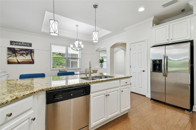 kitchen with visible vents, a sink, a tray ceiling, stainless steel appliances, and light wood finished floors