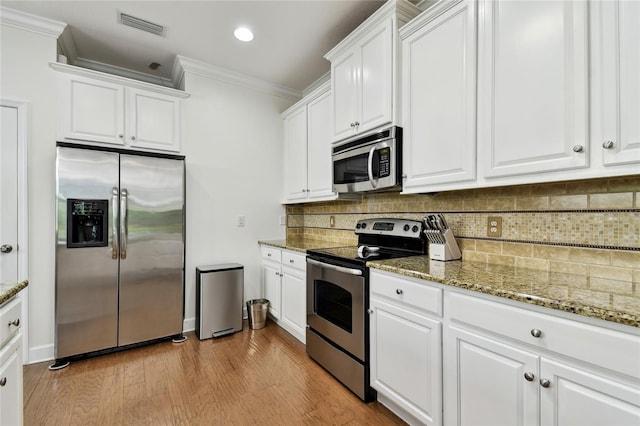 kitchen with visible vents, ornamental molding, white cabinets, appliances with stainless steel finishes, and tasteful backsplash