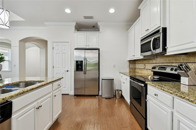 kitchen featuring decorative backsplash, white cabinets, stainless steel appliances, and crown molding