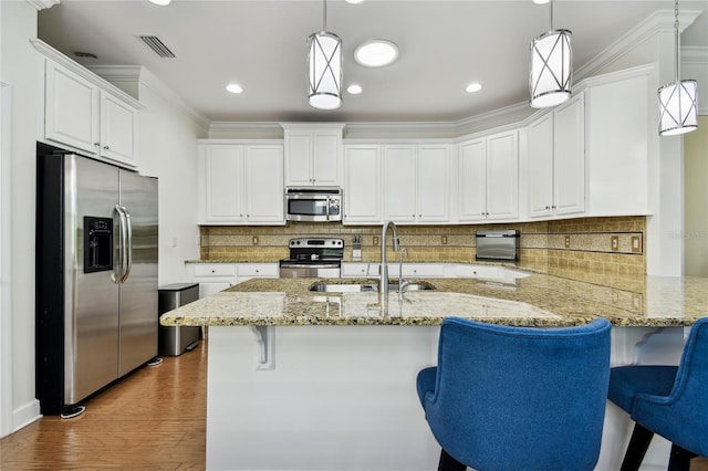 kitchen with visible vents, a sink, stainless steel appliances, a peninsula, and crown molding