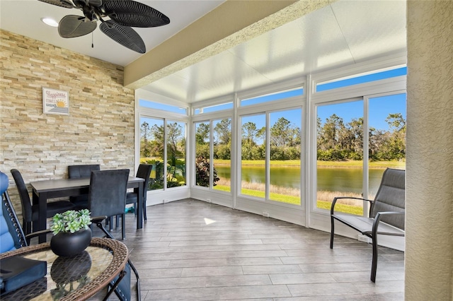 sunroom featuring a water view and ceiling fan