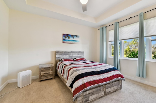 bedroom with a tray ceiling, baseboards, ceiling fan, and carpet flooring