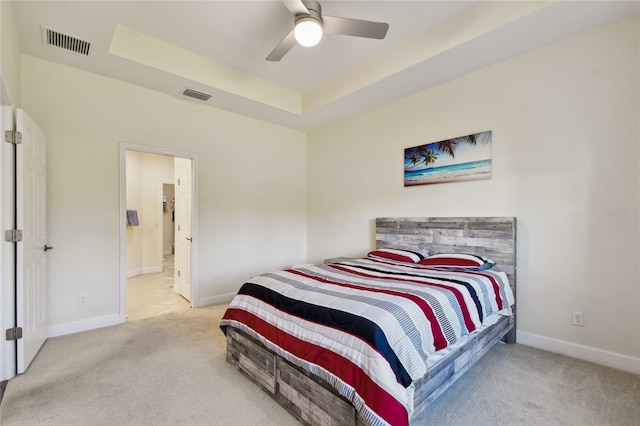 carpeted bedroom with visible vents, a raised ceiling, and baseboards