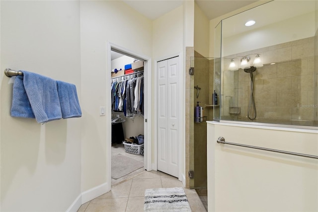 bathroom with tile patterned floors, a shower stall, a spacious closet, and baseboards