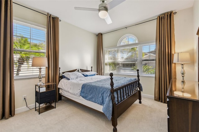 bedroom featuring baseboards, light colored carpet, and a ceiling fan