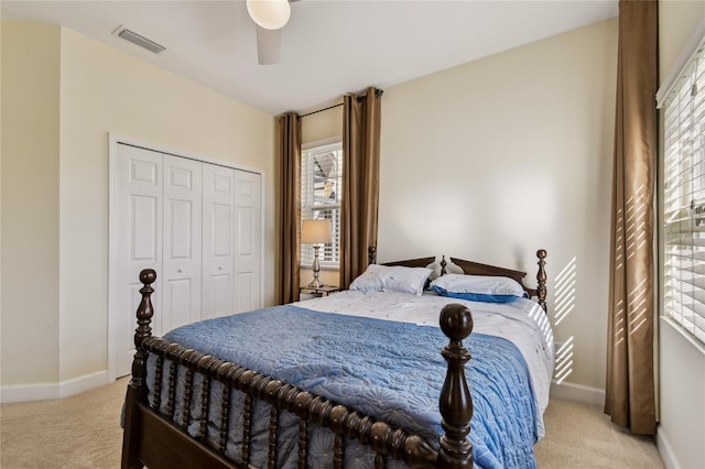 bedroom with light carpet, visible vents, a closet, and baseboards