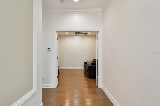 hallway featuring baseboards, crown molding, and hardwood / wood-style flooring