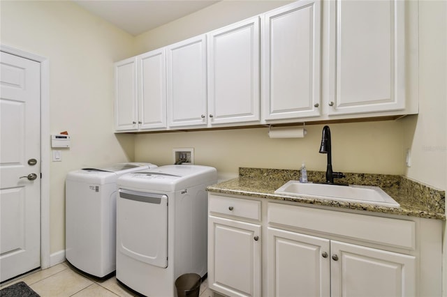 washroom featuring washing machine and clothes dryer, light tile patterned floors, cabinet space, and a sink