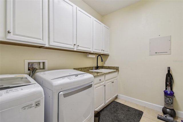 washroom featuring baseboards, washer and clothes dryer, light tile patterned floors, cabinet space, and a sink