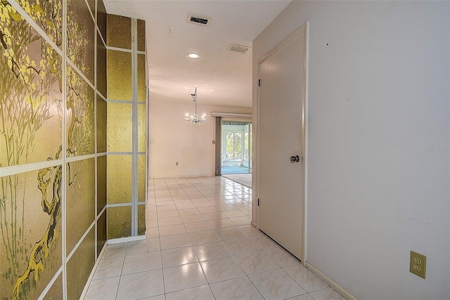 hallway with visible vents, light tile patterned flooring, and a chandelier