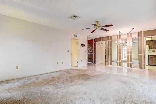 spare room featuring light carpet, visible vents, and a textured ceiling