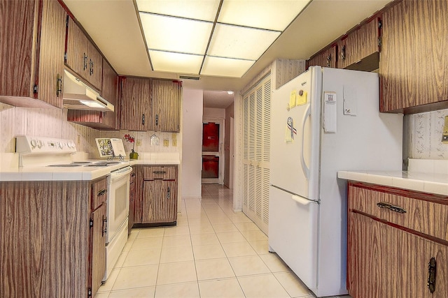 kitchen with white appliances, light tile patterned floors, decorative backsplash, light countertops, and under cabinet range hood