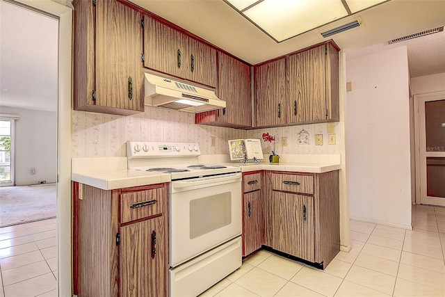 kitchen with under cabinet range hood, electric range, visible vents, and light tile patterned floors