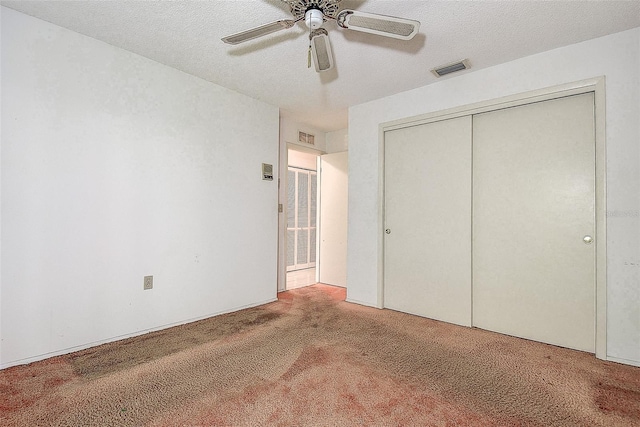 unfurnished bedroom with visible vents, carpet floors, a textured ceiling, and a closet