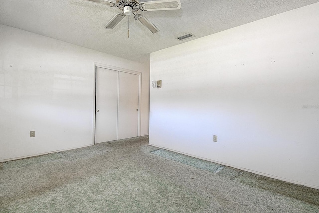 unfurnished room featuring carpet flooring, a textured ceiling, visible vents, and a ceiling fan