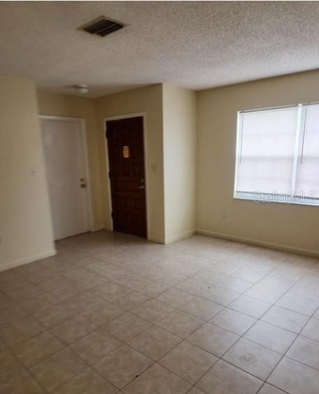 spare room with a textured ceiling, visible vents, and baseboards