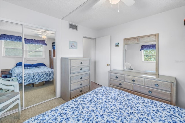 bedroom featuring a textured ceiling, carpet flooring, visible vents, a ceiling fan, and a closet