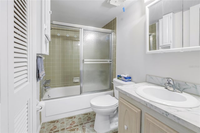 bathroom featuring toilet, combined bath / shower with glass door, and vanity