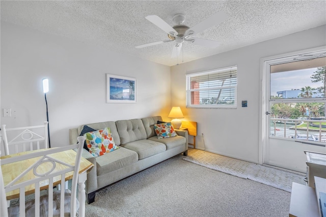 carpeted living area with a textured ceiling and a ceiling fan