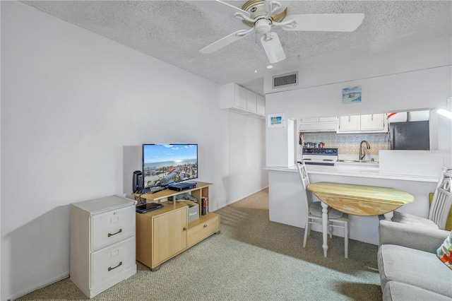 interior space featuring ceiling fan, visible vents, a textured ceiling, and light colored carpet