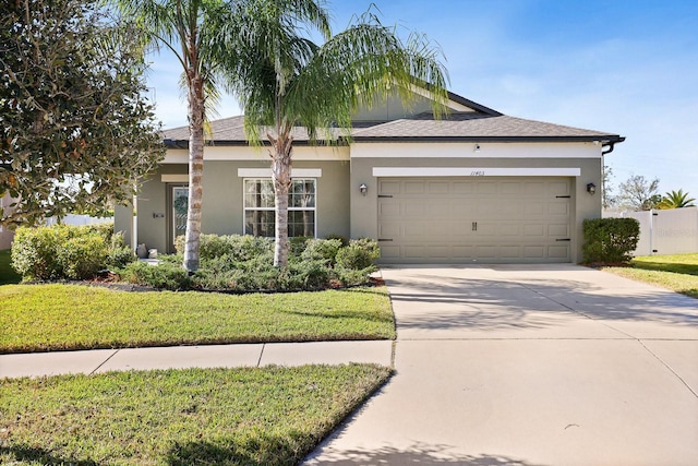 view of front of house featuring a garage, a front yard, concrete driveway, and stucco siding